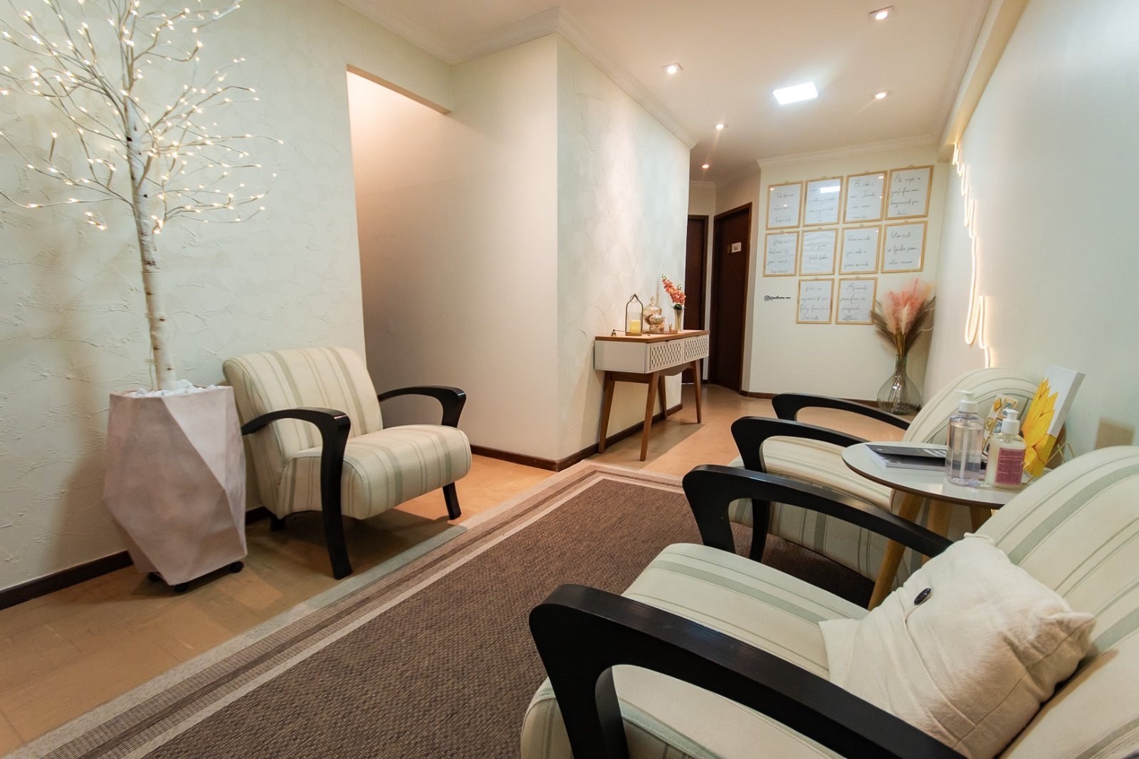 A sala de espera, com poltronas listradas, um tapete e a árvore de luzinhas no canto.